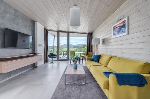 a living room with a yellow couch and a tv at Apartmány HRÁDEČEK in Mladé Buky