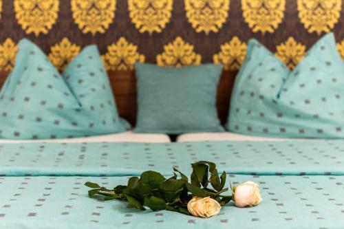 a bed with blue pillows and flowers on a table at Kőszeg Panzió in Kőszeg