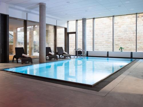 a large pool in a building with chairs and tables at Hotel TAMMEL in Jičín
