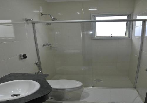 a bathroom with a shower and a toilet and a sink at Hotel das Acacias in São Sebastião do Paraíso