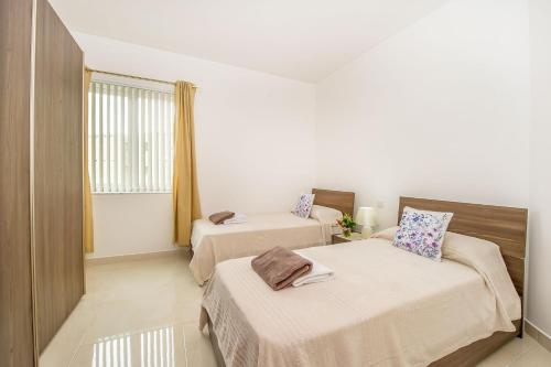 a hotel room with two beds and a window at Hillock Residence Apartments in Marsalforn
