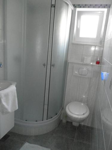 a bathroom with a shower and a toilet and a window at Apartments Rinčić in Marina
