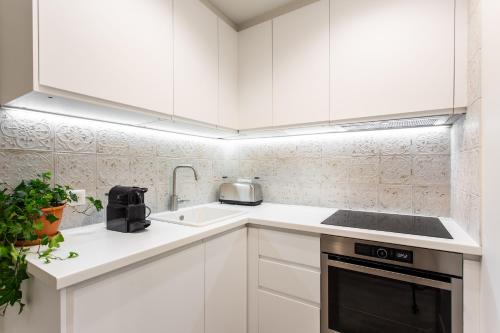 a white kitchen with white cabinets and a sink at Dreamyflat - Ste Croix in Paris