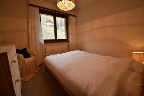 a bedroom with a white bed and a window at Apartment Mont-Parrain in La Tzoumaz