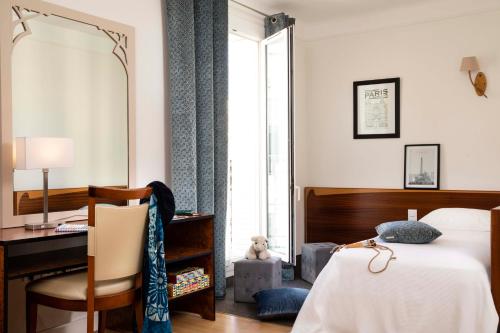 a bedroom with a bed and a desk and a mirror at Grand Hotel des Balcons in Paris