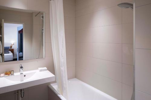 a bathroom with a tub and a sink and a shower at Grand Hotel des Balcons in Paris