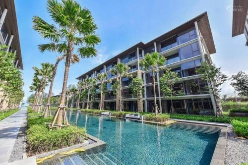 an exterior view of a building with a swimming pool and palm trees at Baan Mai Khao in Mai Khao Beach