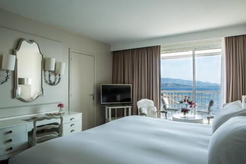 a hotel room with a large bed and a large window at Sofitel Golfe d'Ajaccio Thalassa Sea & Spa in Ajaccio