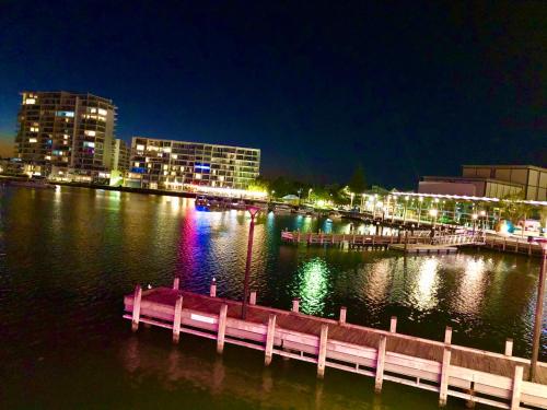 a dock in the water with a city at night at Relaxed Ocean View in Mandurah