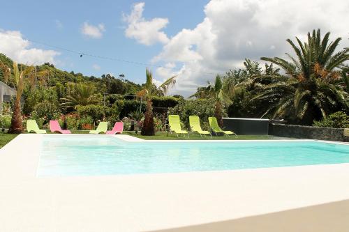 una piscina con tumbonas verdes y rosas en Quinta de Santa Bárbara Casas Turisticas, en Lagoa