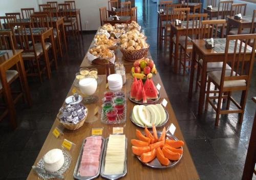 a long table with fruits and vegetables on it at Hotel das Acacias in São Sebastião do Paraíso
