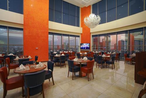 a dining room with tables and chairs and windows at Ramada Encore by Wyndham Kuwait Downtown in Kuwait