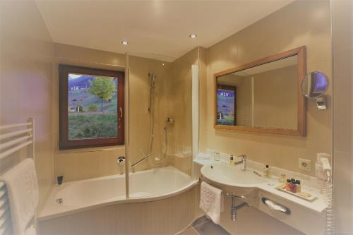 bagno con vasca, lavandino e specchio di Hotel Montana a Sankt Anton am Arlberg