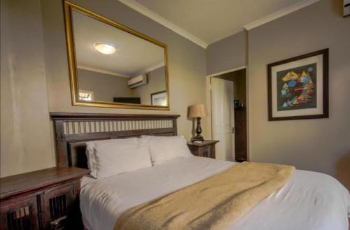 a bedroom with a bed with a large mirror at Mount Edgecombe Guest House in Mount Edgecombe