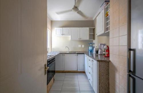 a kitchen with white cabinets and a stove top oven at Mount Edgecombe Guest House in Mount Edgecombe