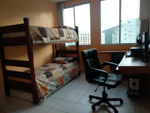 een slaapkamer met 2 stapelbedden, een bureau en een stoel bij Quarto com café nas Pitangueiras in Guarujá