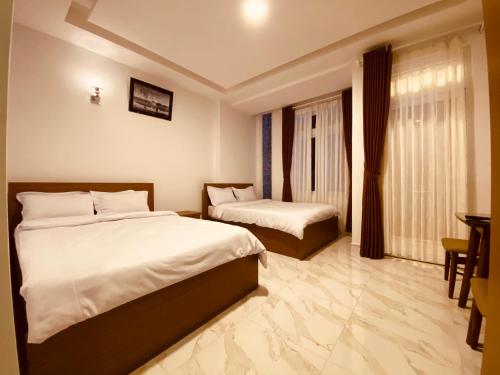 Cette chambre comprend 2 lits et une table. dans l'établissement Thanh Dat Hotel, à Đà Lạt