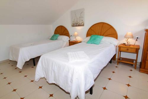 フエンヒロラにあるApartamento Torreblanca, Fuengirolaのベッドルーム1室(白いシーツと青い枕のベッド2台付)