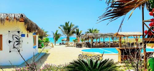 um resort com piscina, mesas e cadeiras em Palo Santo Beach club em Bocapán