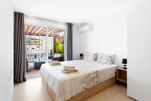 a white bedroom with a bed and a large window at Villa Chispita & Sevilla Torreblanca in Fuengirola