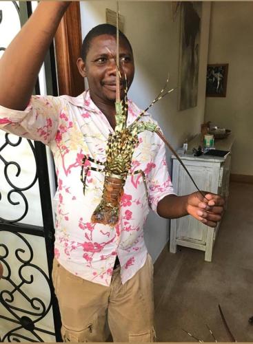 a man is holding a stick with a plant at Rafiki Village in Watamu
