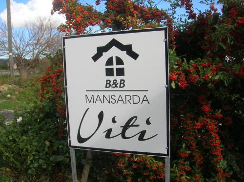 a sign in front of a bush with red flowers at MANSARDA VITI - Sguardo su Frontone - in Frontone