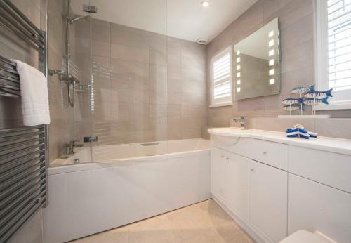 a white bathroom with a tub and a sink at Mawgan Porth Apartments in Mawgan Porth