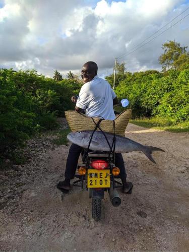 a man riding a motorcycle on a dirt road at Rafiki Village in Watamu