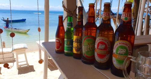 a group of beer bottles sitting on a table on the beach at Hotel ECOLODGE LE RAVORAHA in Sainte Marie