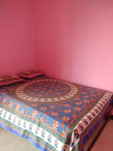 a bedroom with a bed in a room with pink walls at Om Ganesh Naik Guest House in Arambol