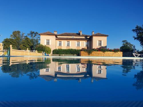 une maison avec sa réflexion dans l'eau dans l'établissement Residence Chateau de Barbet, à Lombez
