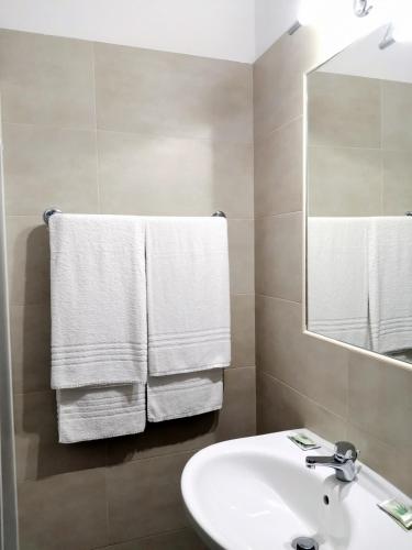 a bathroom with a sink and a mirror and towels at H&L Hotel in Cinisello Balsamo