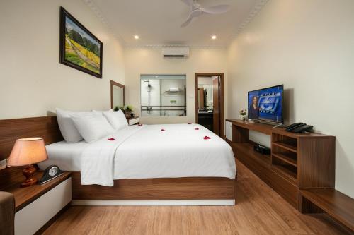 a bedroom with a large white bed and a desk at Tam Coc Holiday Hotel & Villa in Ninh Binh