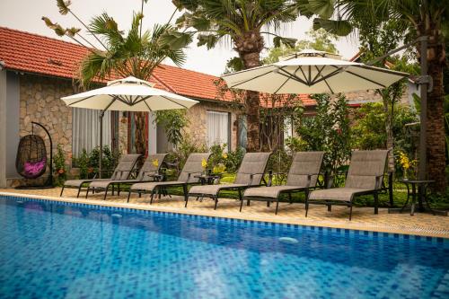 grupa leżaków i parasoli przy basenie w obiekcie Tam Coc Holiday Hotel & Villa w mieście Ninh Binh