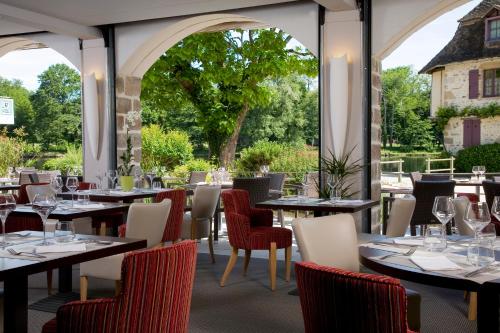 ボーリュー・シュル・ドルドーニュにあるLogis hotel les flots bleusのテーブルと椅子、大きな窓のあるレストラン
