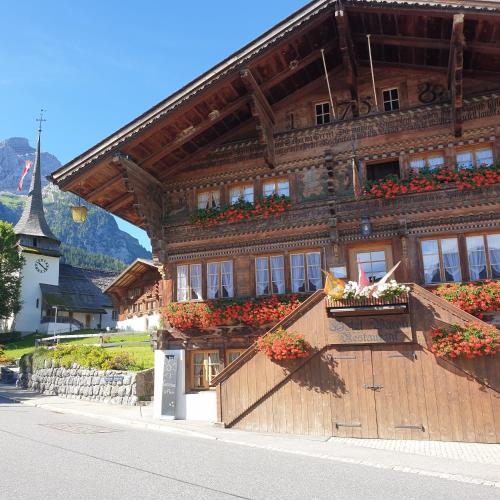 a large wooden building with flowers in front of it at Hotel Bären in Gsteig