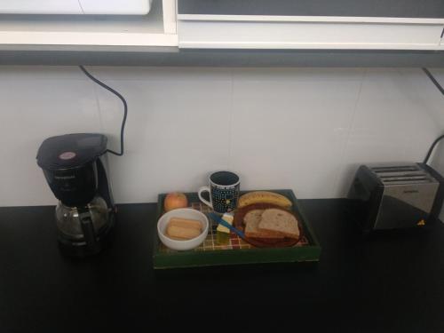 een dienblad met eten op een aanrecht, met een bord brood ernaast bij Quarto com café nas Pitangueiras in Guarujá
