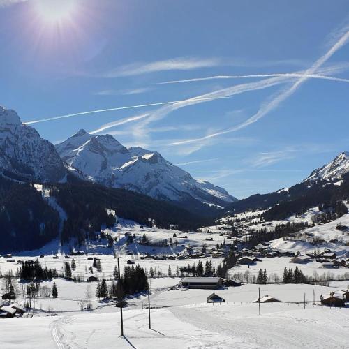 a view of a snow covered mountain range with the sun at Hotel Bären in Gsteig