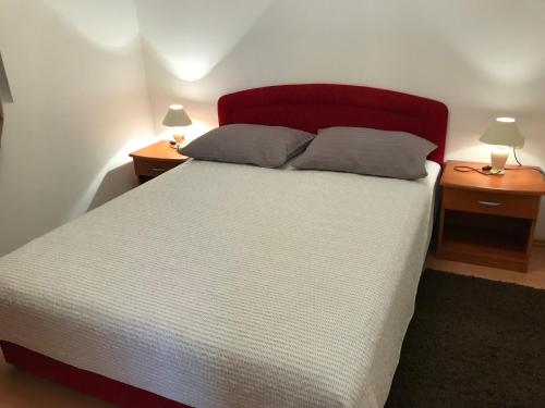 a bed with a red headboard and two night stands at Holiday Home Panorama in Zubovići