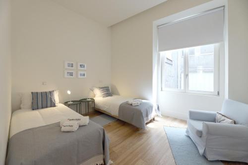 een witte kamer met 2 bedden en een bank bij FLH Sá da Bandeira Luxury Apartment in Porto