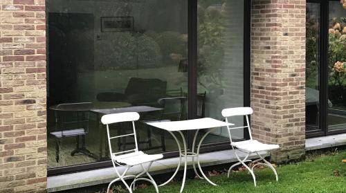 Le porche في Lasne: مجموعة من الكراسي البيضاء وطاولة في النافذة