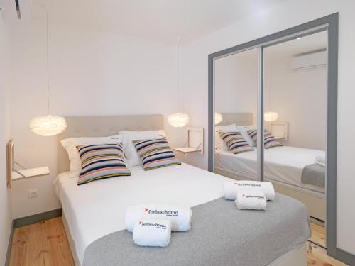 a white bedroom with two beds and a mirror at FLH Porto Modern Apartment in Porto