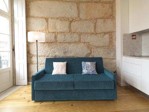 ein blaues Sofa in einem Zimmer mit Ziegelwand in der Unterkunft FLH Porto Cozy Studio in Porto