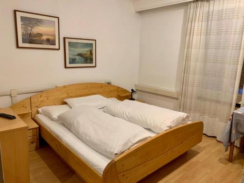 a wooden bed with white pillows in a room at B&B Hotel Dolomiti in Bolzano