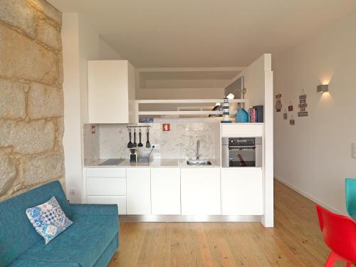 eine Küche mit weißen Schränken und einer blauen Couch in der Unterkunft FLH Porto Cozy Studio in Porto