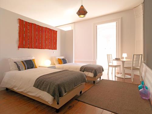 a bedroom with two beds and a table and a window at FLH Porto Charming Studio in Porto