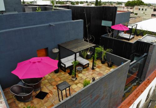a patio with a table and pink umbrellas on a roof at Elena de Cobre, Leon, a Member of Design Hotels in León