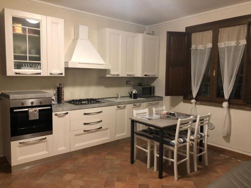 a kitchen with white cabinets and a table with chairs at Casa in campagna a due passi dal mare in Pisa
