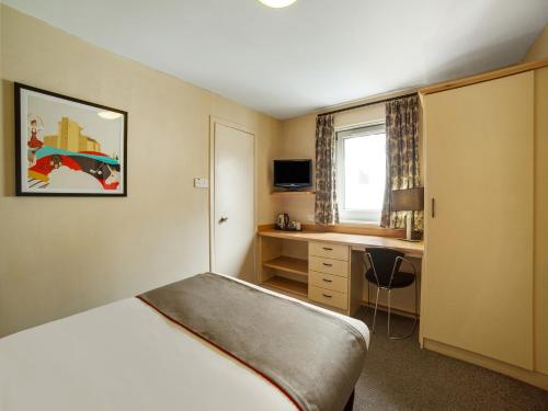 a hotel room with a bed and a desk at OYO Flagship Brentwood in Aberdeen