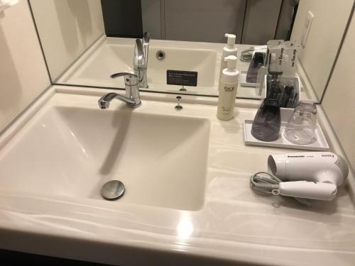a bathroom sink with toothbrushes and toothpaste at Dormy Inn Higashi Muroran in Muroran